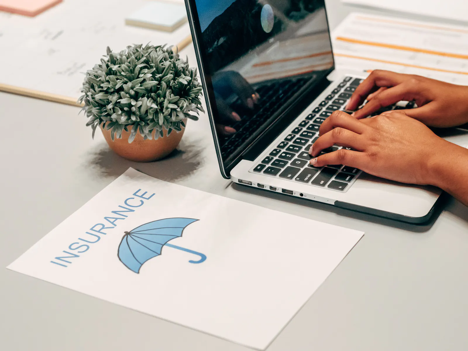 Insurance agency professional working on a laptop beside policy materials