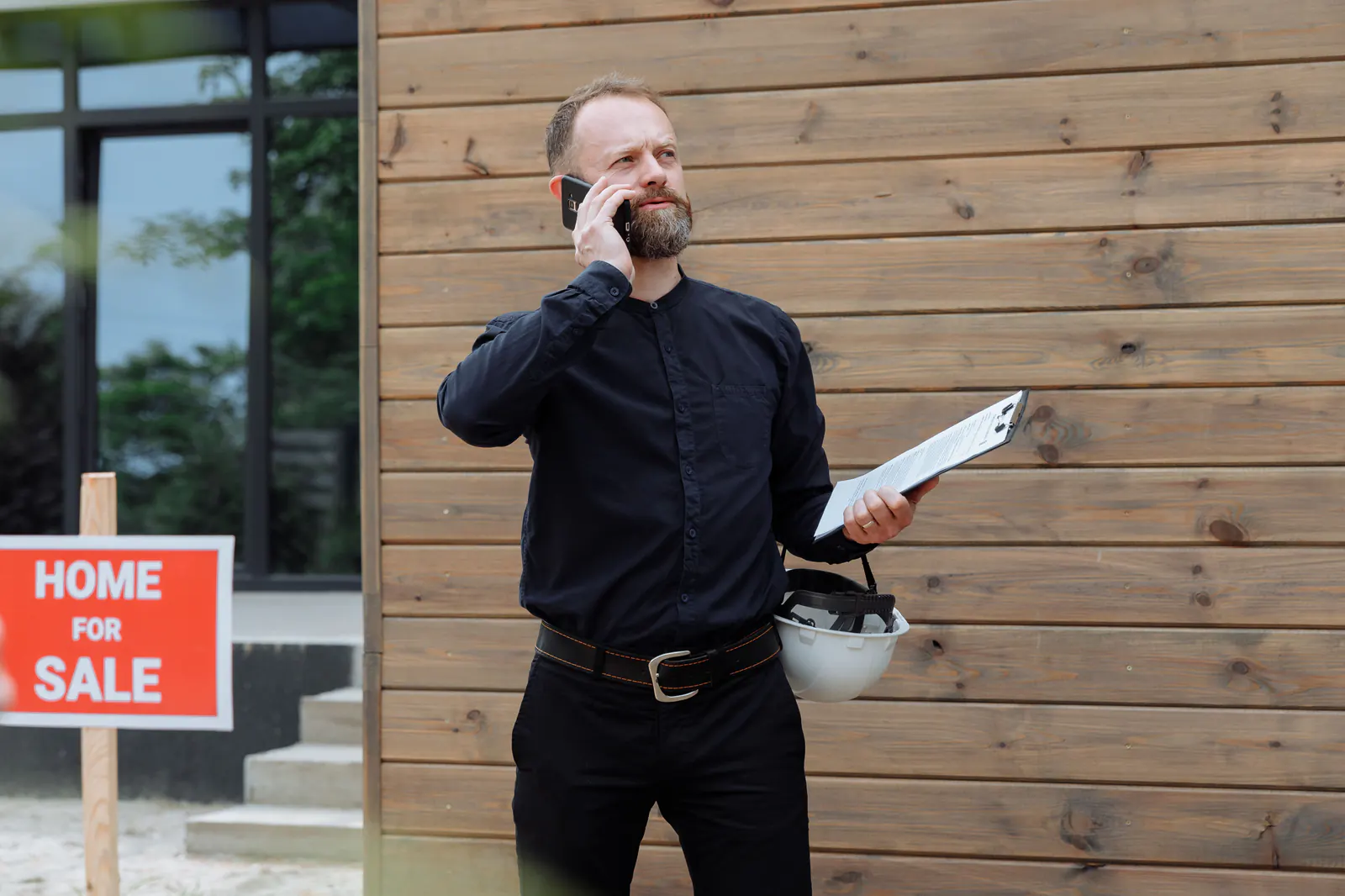 Real estate professional handling a call outside a home for sale