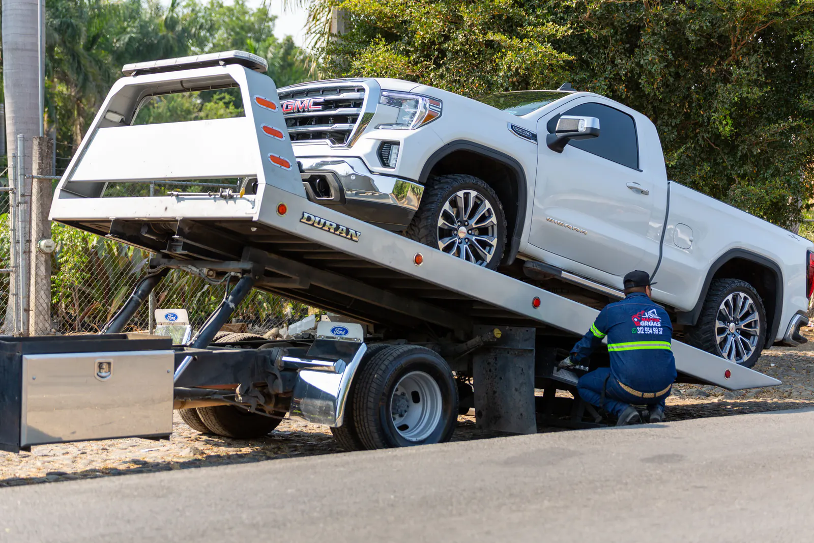 Tow truck operator loading a pickup onto a flatbed