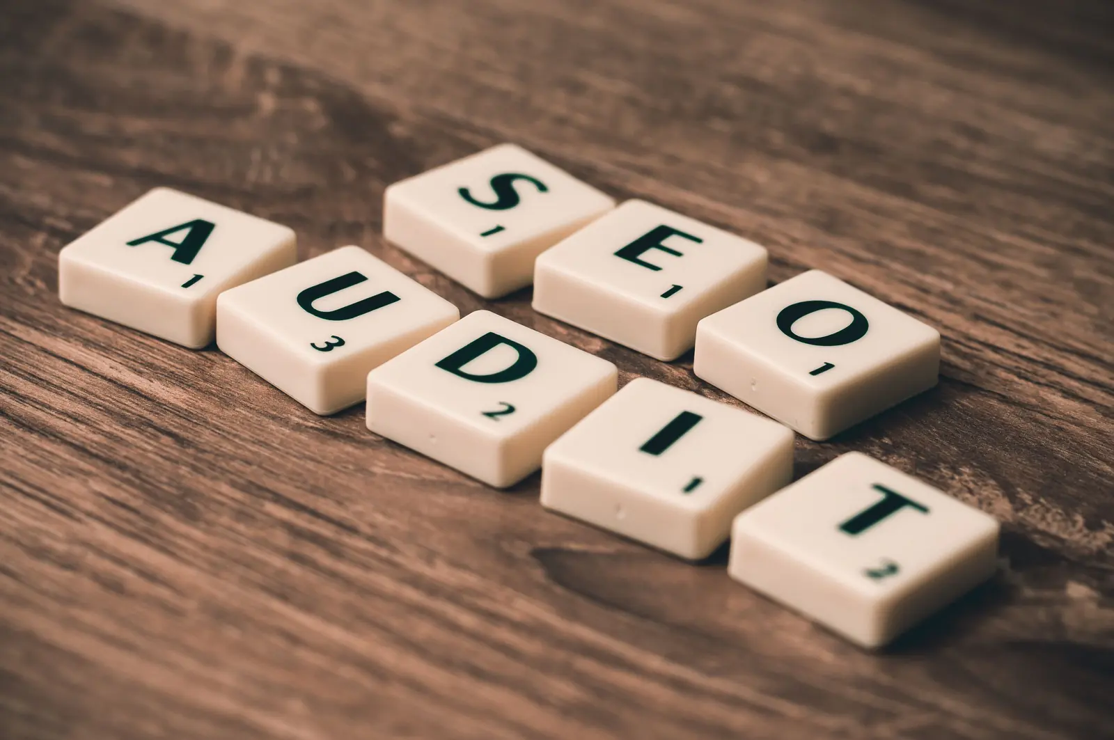 SEO audit concept spelled with letter tiles beside a magnifying glass